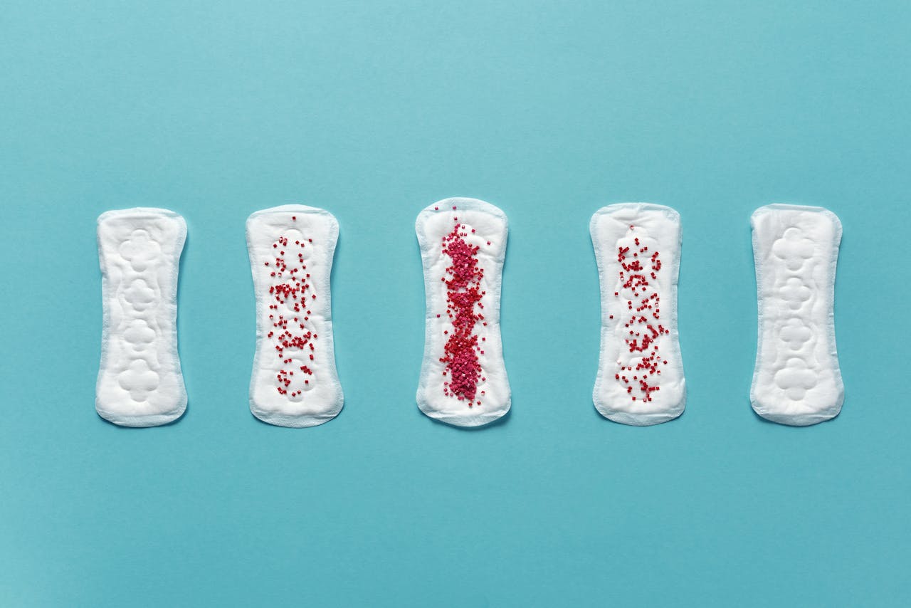 Various menstrual pads arranged on a blue background showcasing stages of use.